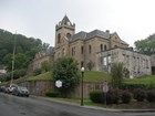 Stone building on a hill with a large square tower in the center. 