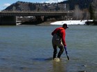 A scientist standing in very shallow water holding a water quality probe