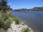 A clipboard and river measurement equipment on the bank of a river with a bridge in the distance