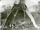 A black and white photo of Tukudika people sitting inside a tent.