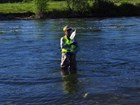 A person holding a bottle and water quality equipment standing in a river