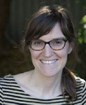 Headshot of a white woman wearing glasses smiling