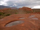 Eroded depressions in the sandstone filled with water.