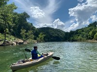 A kayaker paddles downriver in front of us.
