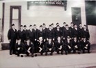 A formal portrait of men in uniform outside a building.