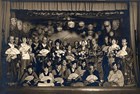 A black and white photo of men and women on stage for a performance.
