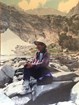 Woman sits on rocks in front of mountains