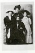 Three women stand around a seated man