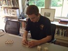 Volunteer sits at table building small balsa wood bridge
