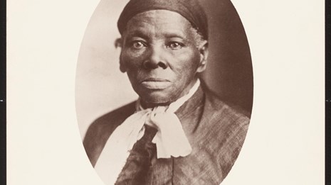 Harriet Tubman stares stoically into the camera infront of her.