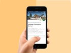 Hand holds phone with mobile app. App shows a visitor center. Orange background.