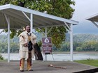 Man wearing early 1800s buckskin historic reenactment clothing stands on a riverfront pavilion.
