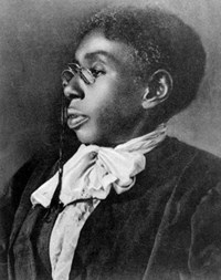 Portrait of well dressed Black woman in round spectacles, short natural hair, and lacy white collar