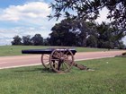 Cannon sits in grassy field, divided by highway