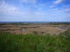 Blue skies above a saltmarsh and vacation houses in the background on the Cape Cod Bay in Truro, MA.