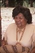 Older woman  in peach blouse holds hand woven basket