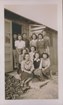 11 Japanese women and 3 men pose for on the front steps of wooden building, sign reads 