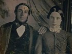 A faded portrait of man with hand on woman's shoulder, sitting for professional picture. 