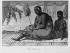 Hawaiian woman and young man sitting in lush pavilion both holding ornate staffs. Ship in background
