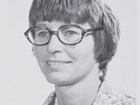 Woman with short hair and glasses smiles for the camera.