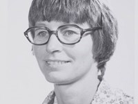 Woman with short hair and glasses smiles for the camera.