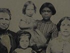 Group portrait of white family. Young, dark skinned indigenous women holds infant in background