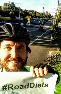 Wayne Emington with bike helmet holding sign that reads #RoadDiets