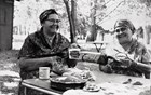 Two women smiling and holding beading implements