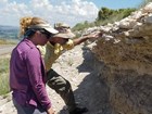 photo of 2 people examining a rock outcrop