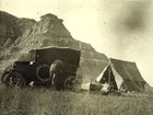 historic photo of a camper with a truck and tent in a field