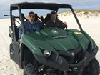 photo of 2 people sitting in an off road vehicle on a beach