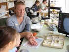 photo of a paleontologist talking with children in a fossil lab