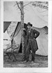 Ulysses S Grant standing by a tree with a tent in the background.