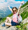 A happy child sitting on a rock on a mountainside.