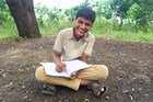 A happy boy sitting cross-legged, writing in a journal.