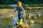 A child plays on the rocks in a stream.