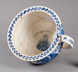 A large bowl with a handle. It has a decorative edge and a portrait of a man on the interior.