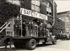 Black and white photo of men in uniform standing on the bed of a truck.