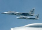 Three silver military jets flying in a blue sky.