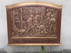 Metal plate showing one soldier on his knees and others standing around him. 