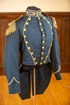 Grey military uniform adorned with golden buttons and golden shoulder pads with frills.