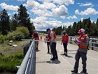 Five scientists standing on a bridge next to a bridge-board and reel used for water monitoring.
