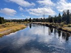 A view of a tree-lined river from a bridge with a parking area at the bend in the river.