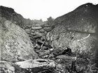 An 1863 photo in stark black and white depicts a dead US soldier in a trench fortified by rocks.