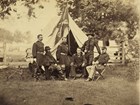 A general and five of his commanders pose outside a tent in an 1864 photo.