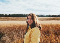 person smiling at camera with savannah field