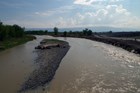 A river paralleling a dirt road and a short gravel bar in the center.