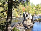 Photo of a rock outcrop in a stream with forested banks.