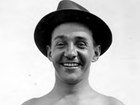 Black-and-white photo of smiling man in hat.