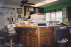 Old wooden desk with papers piled high all over it.